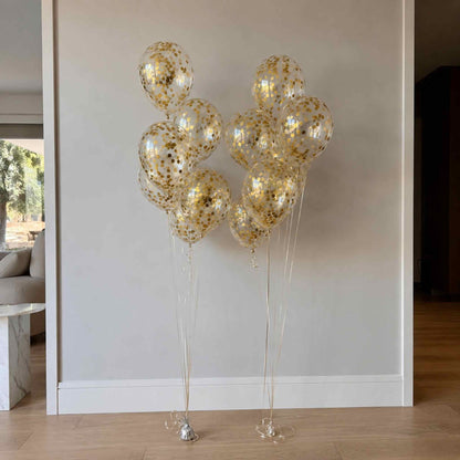 Gold confetti balloons against a neutral wall