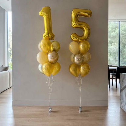 Gold number balloons spelling '15' in a room with a couch and window.