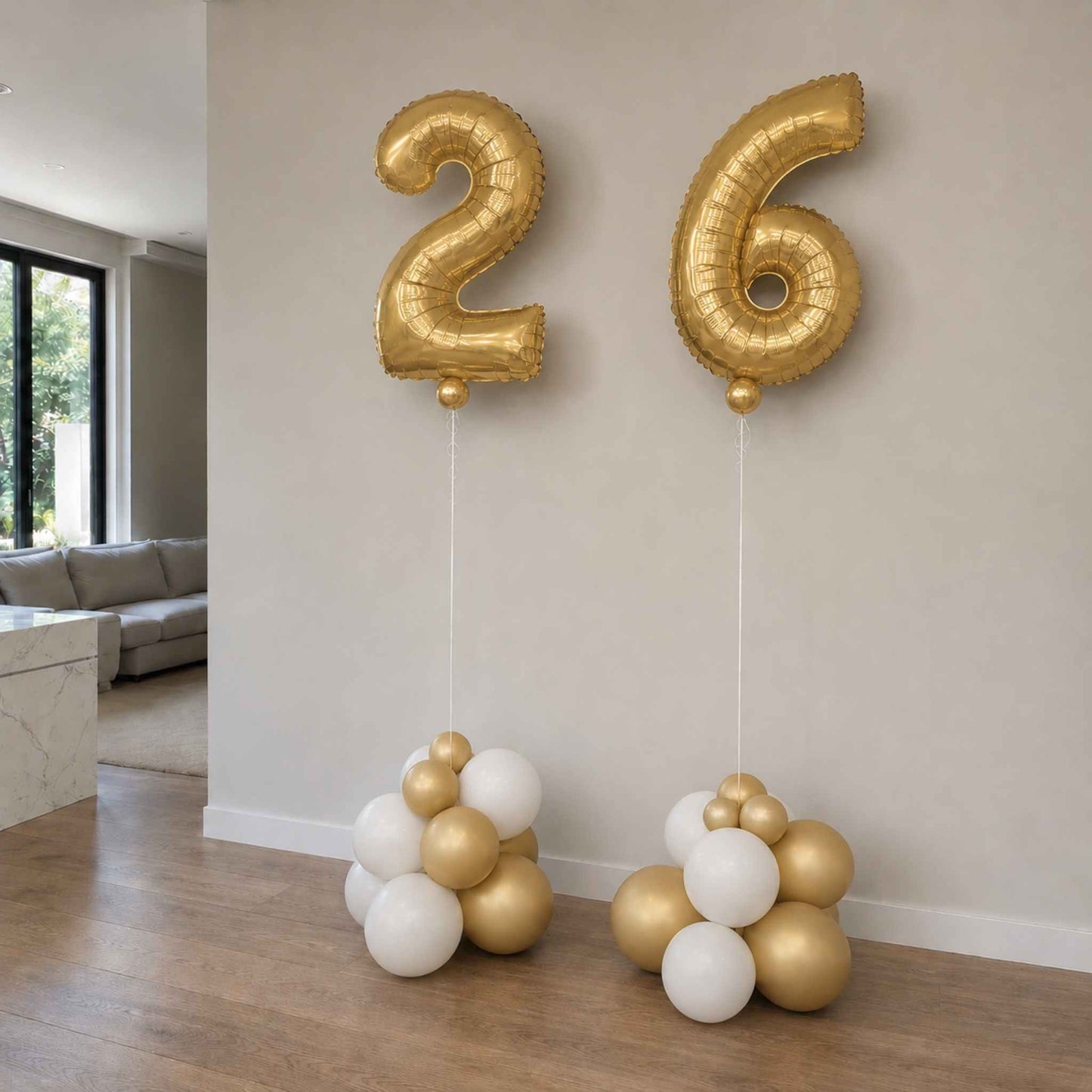 Gold and white balloons shaped like the number 26 in a living room setting.