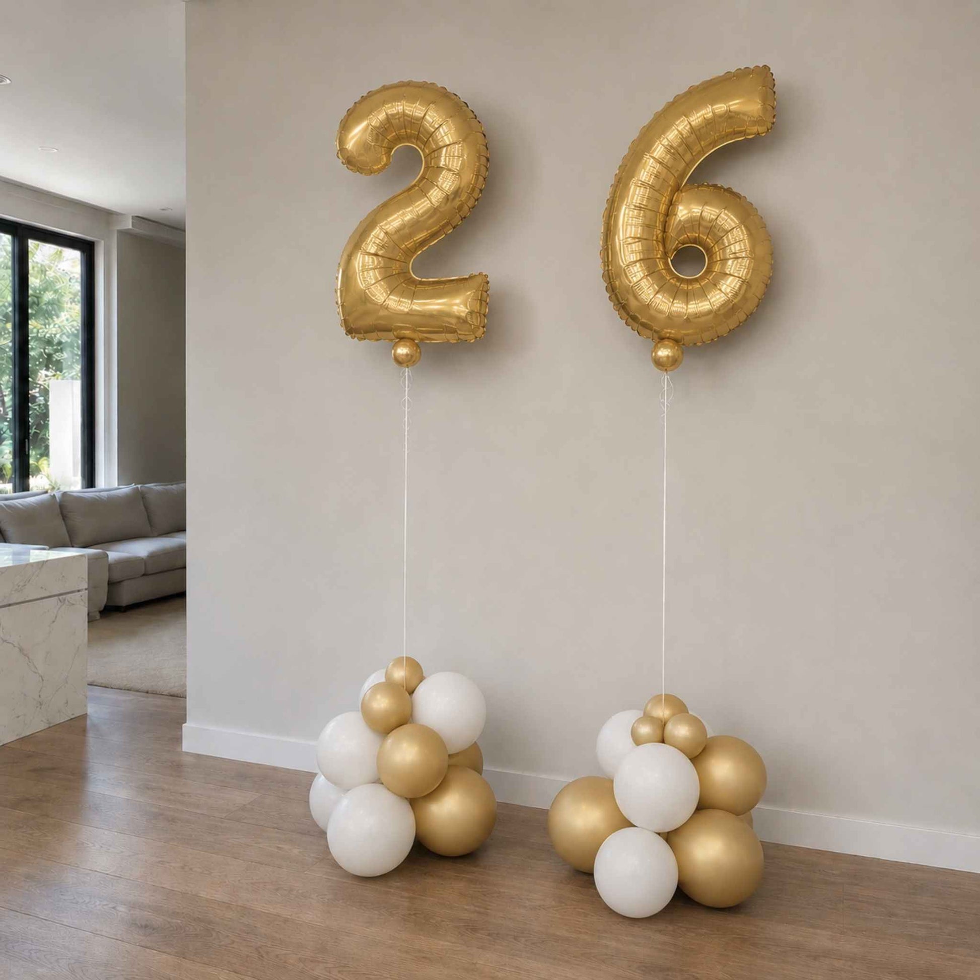 Gold and white balloons shaped like the number 26 in a living room setting.