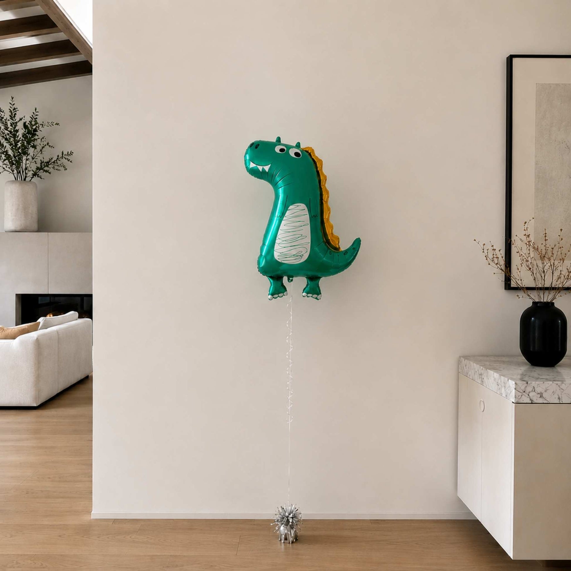Dinosaur-shaped balloon in a living room setting with a neutral wall and decor.