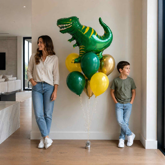 Woman and child standing with a large green dinosaur balloon and smaller balloons in a modern living room.
