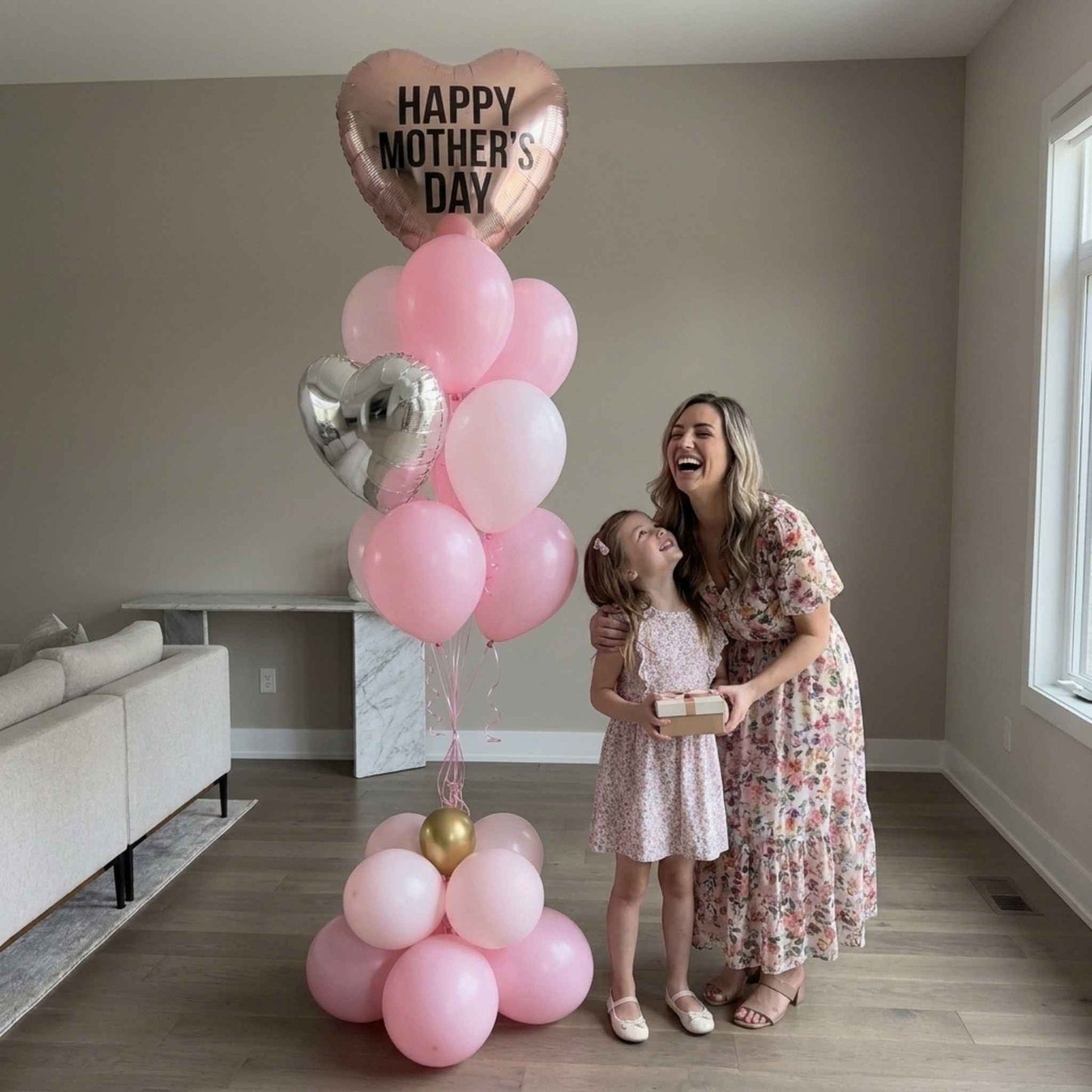 Mother and daughter with pink Mother’s Day balloon bouquet, large house.