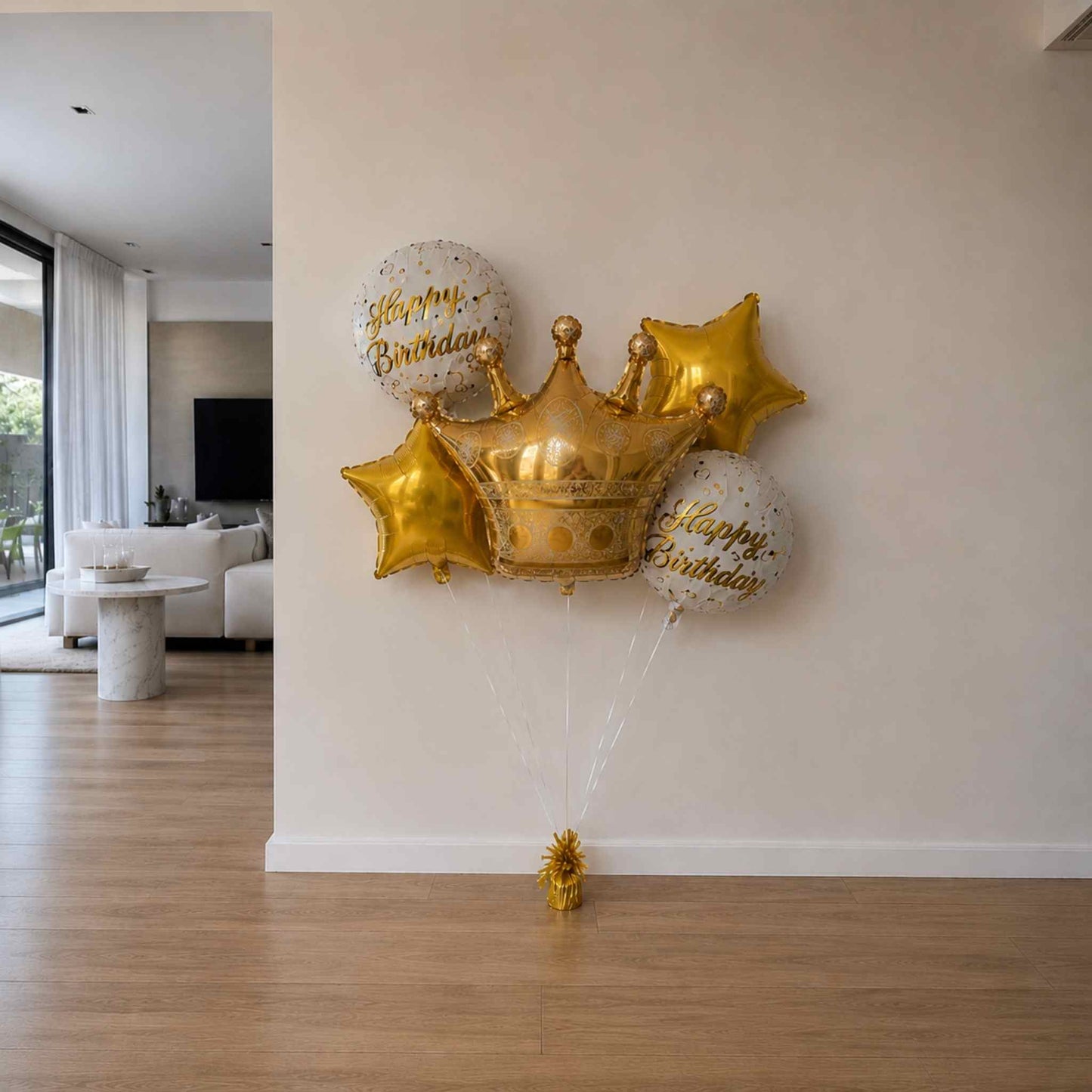 Gold crown-shaped balloon with 'Happy Birthday' text against a white wall.