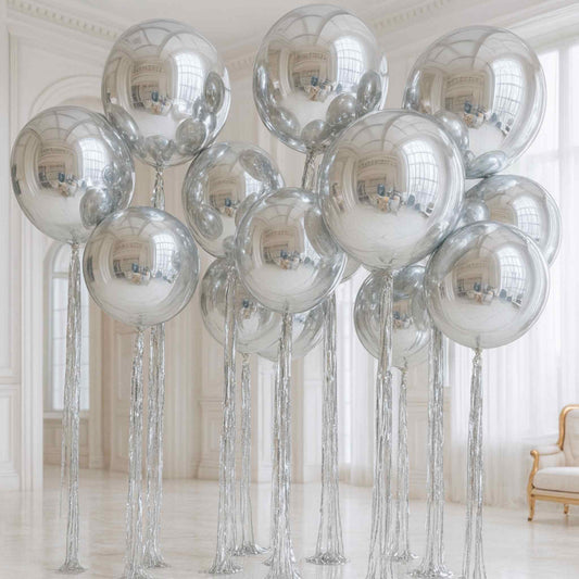 Silver reflective balloons with tassels in a room with white walls and a chair.