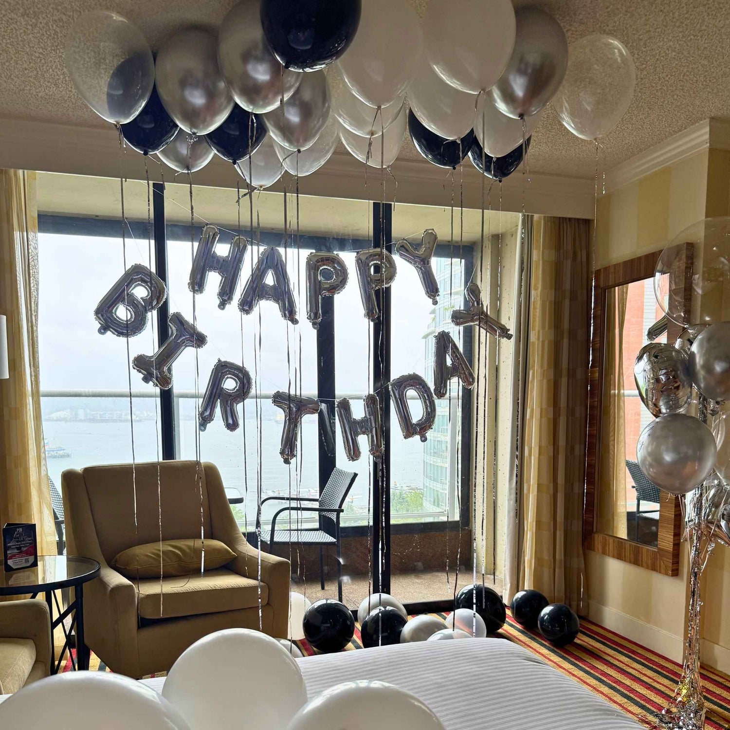 happy birthday hotel room install with black a silver balloons with a foil banner large window
