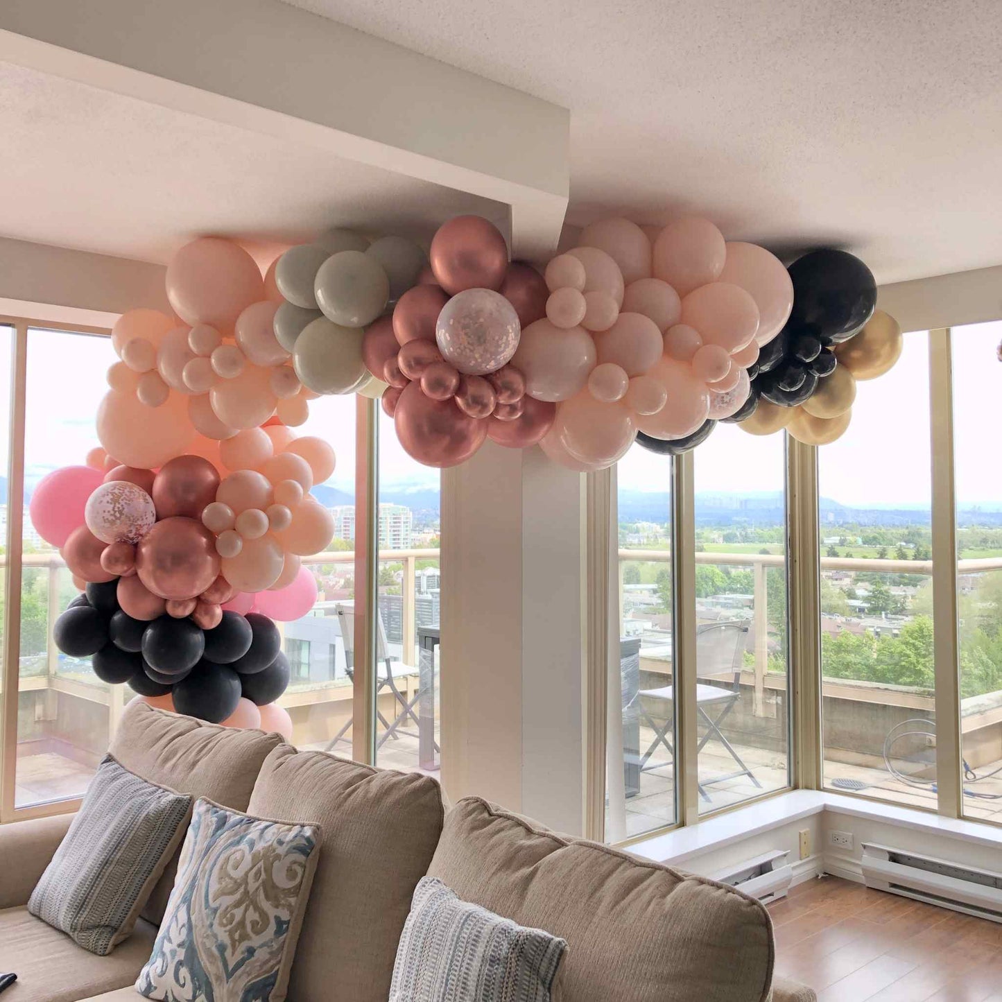 Balloon arch with pink, black, and white balloons in a living room.
