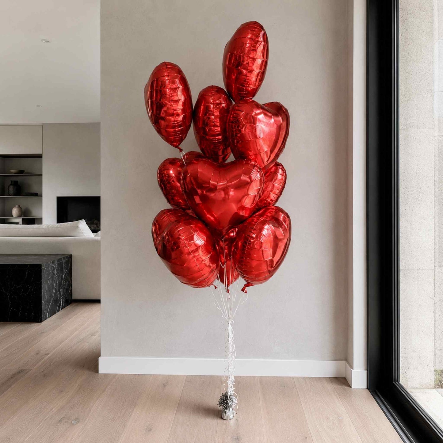 Bouquet of red heart-shaped balloons in a modern living room.