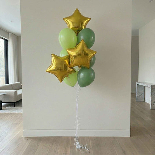 Bouquet of green and gold star balloons against a white wall.