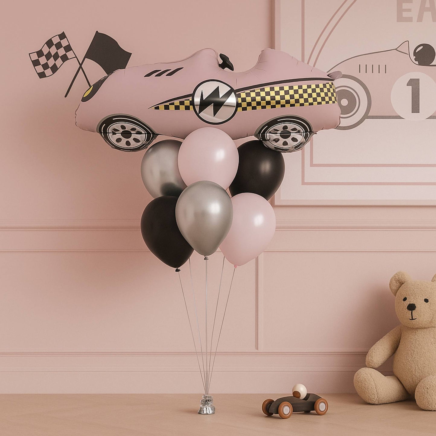 Pink car-shaped balloon with balloons in a room with a teddy bear and toy car.