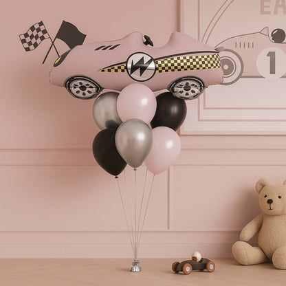 Pink car-shaped balloon with balloons in a room with a teddy bear and toy car.