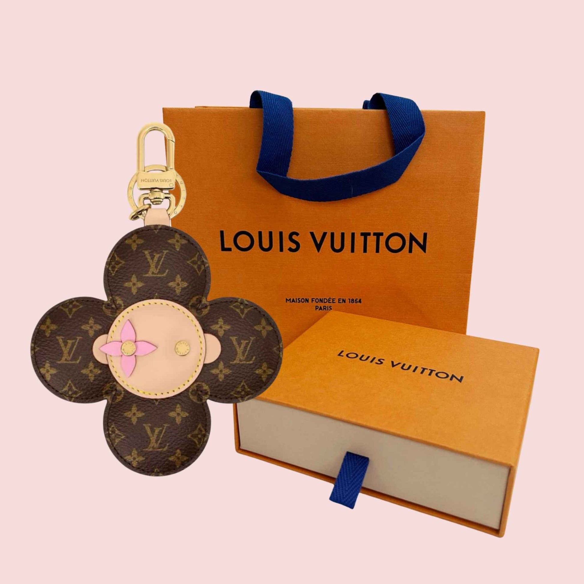 Louis Vuitton keychain and packaging on a pink background
