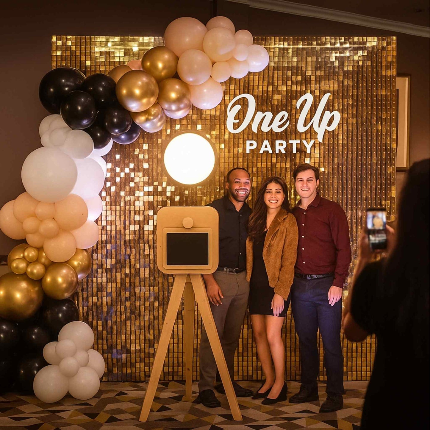 People posing in front of a photo booth with 'One Up Party' backdrop