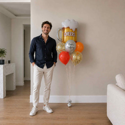 Man standing indoors with balloons including a large beer mug balloon.