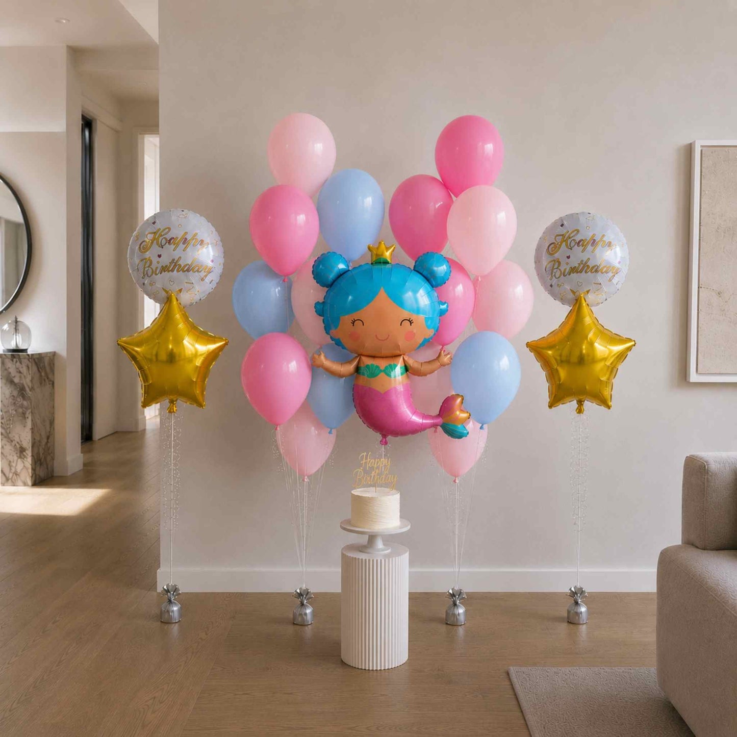 Colorful balloon arrangement with a mermaid balloon and 'Happy Birthday' balloons in a room.