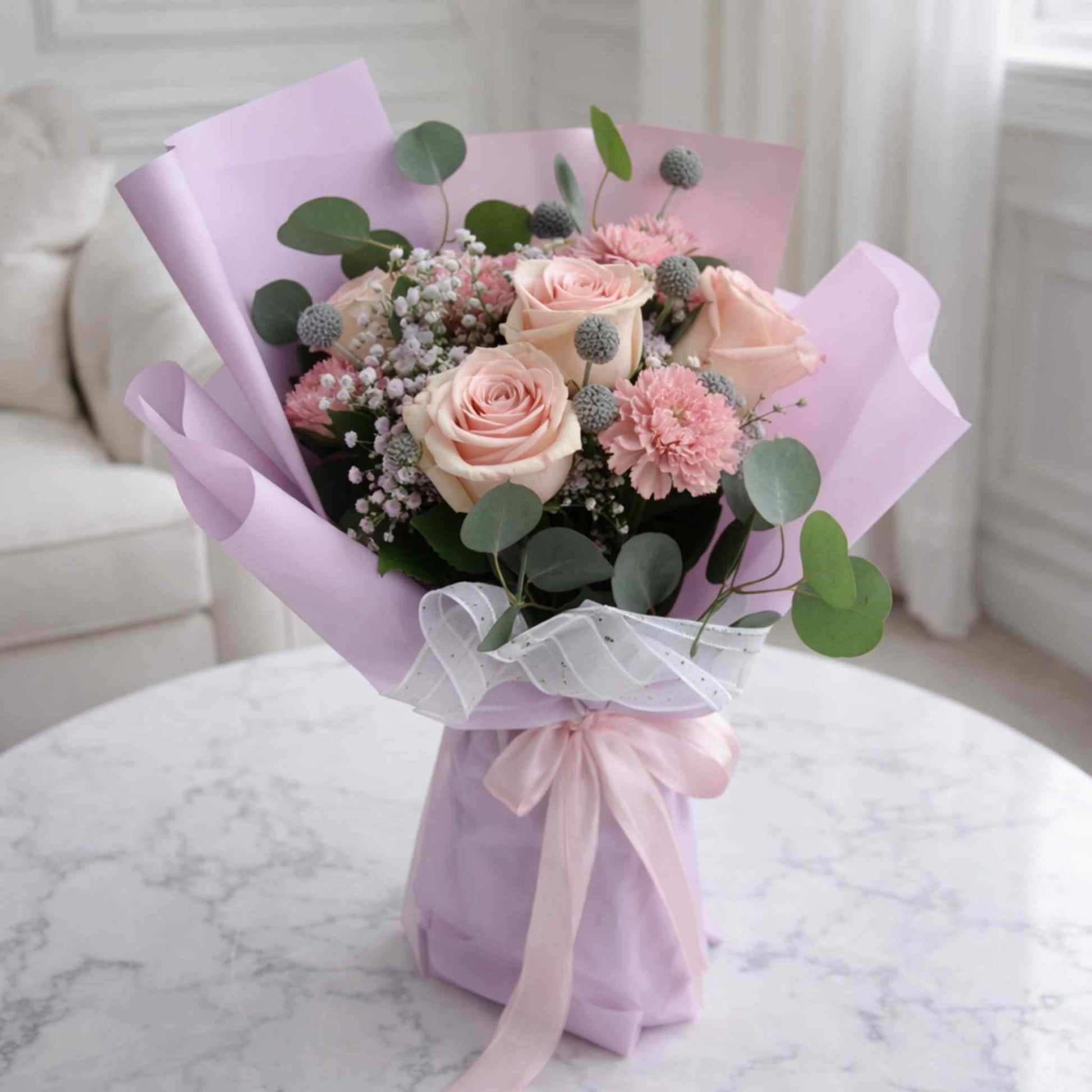 Bouquet of flowers wrapped in pink paper on a marble surface