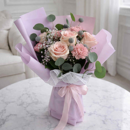 Bouquet of flowers wrapped in pink paper on a marble surface