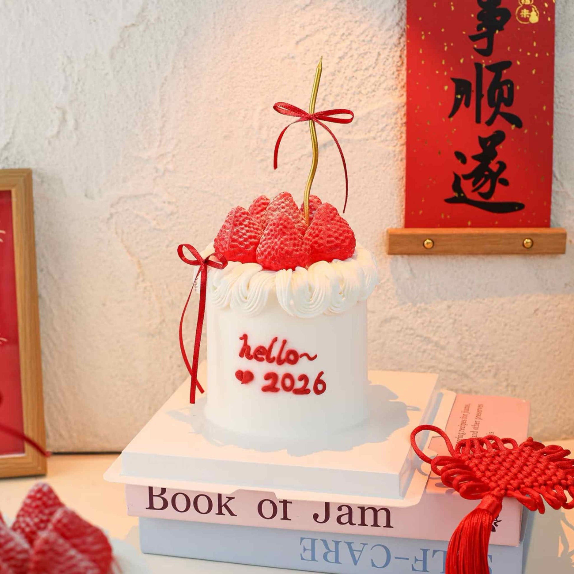Decorative item with red ribbons and 'hello~ 2026' text on a stack of books.