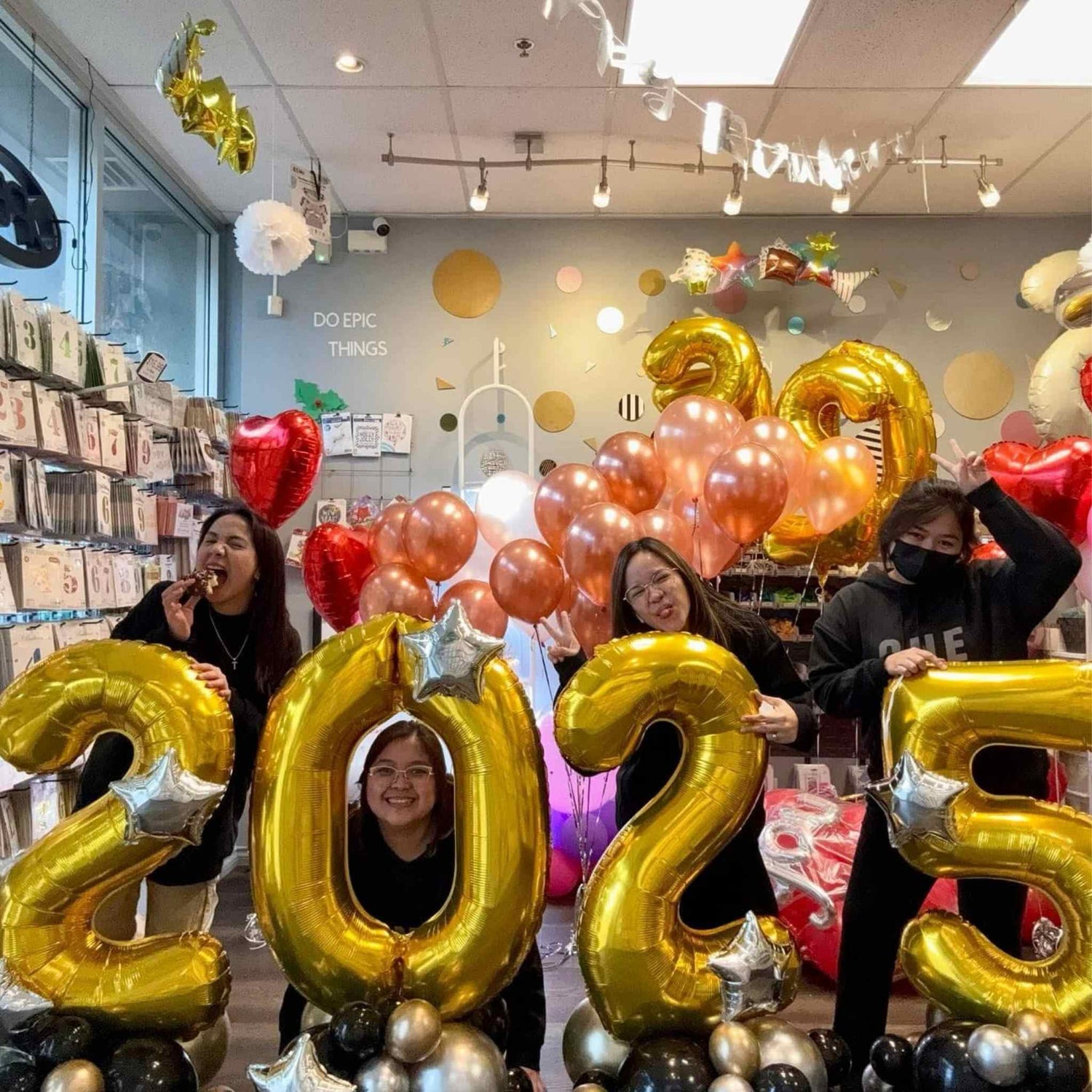 Group of people holding gold '2025' balloons in a store setting.