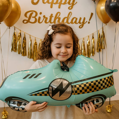 Child holding a large inflatable car balloon with 'Happy Birthday!' decorations in the background.
