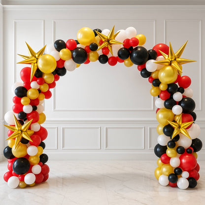 Balloon arch with red, black, gold, and white balloons against a white paneled wall.