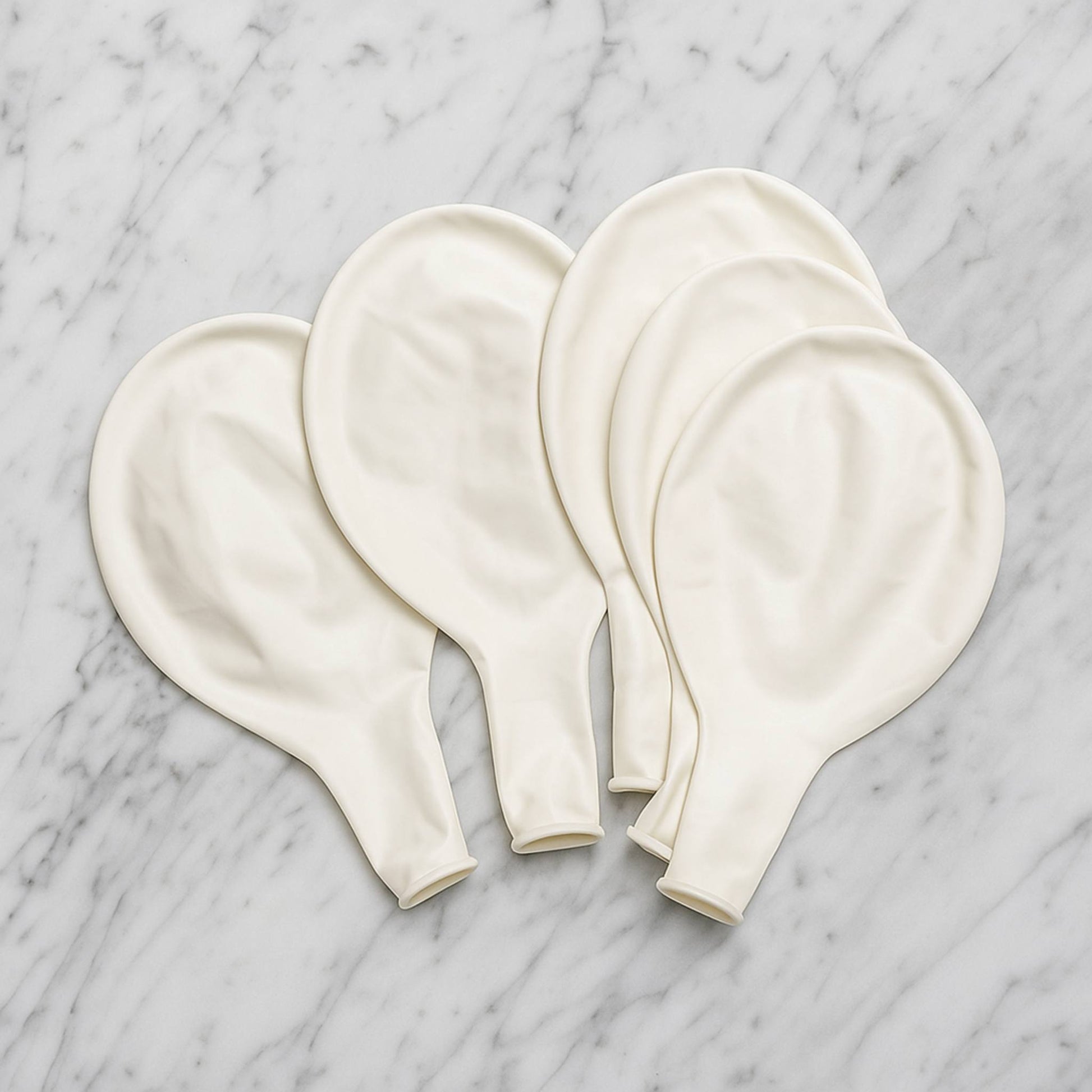Four white balloons on a marble surface