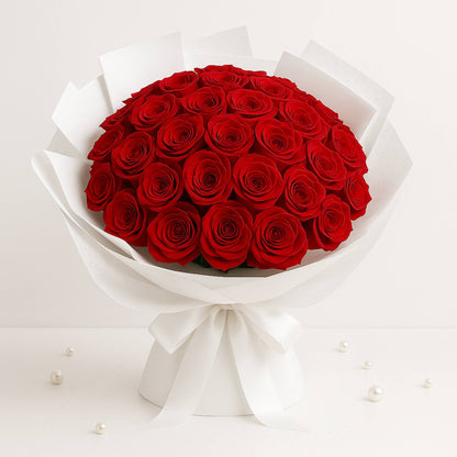 Bouquet of red roses wrapped in white paper on a light gray background