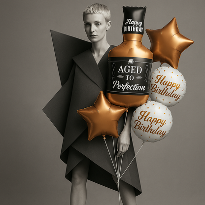 Person holding 'Aged to Perfection' bottle with birthday balloons on a gray background