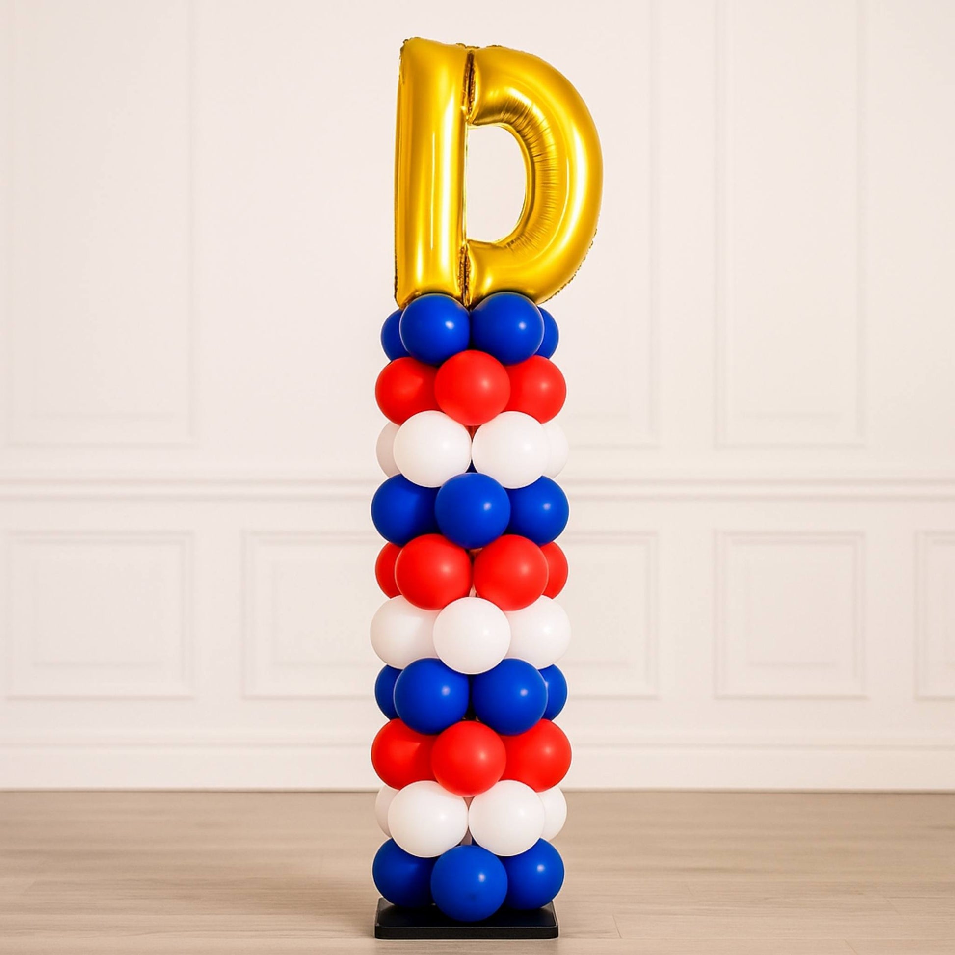 Balloon sculpture with gold letter 'D' on top against a light background