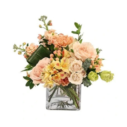 A floral arrangement featuring a variety of flowers including pink carnations, stock, alstroemeria, and lisianthus, in a clear vase.