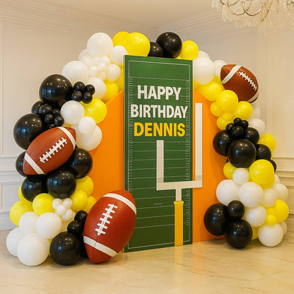 Balloon arch with football decorations and a personalized birthday sign indoors.