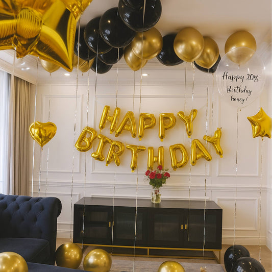 Gold and black balloons spelling 'Happy Birthday' in a room with a vase of flowers on a table.