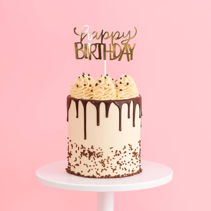 Birthday cake with chocolate drizzle and sprinkles on a pink background