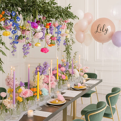 Decorated dining table with flowers, candles, and balloons in a room with white walls.