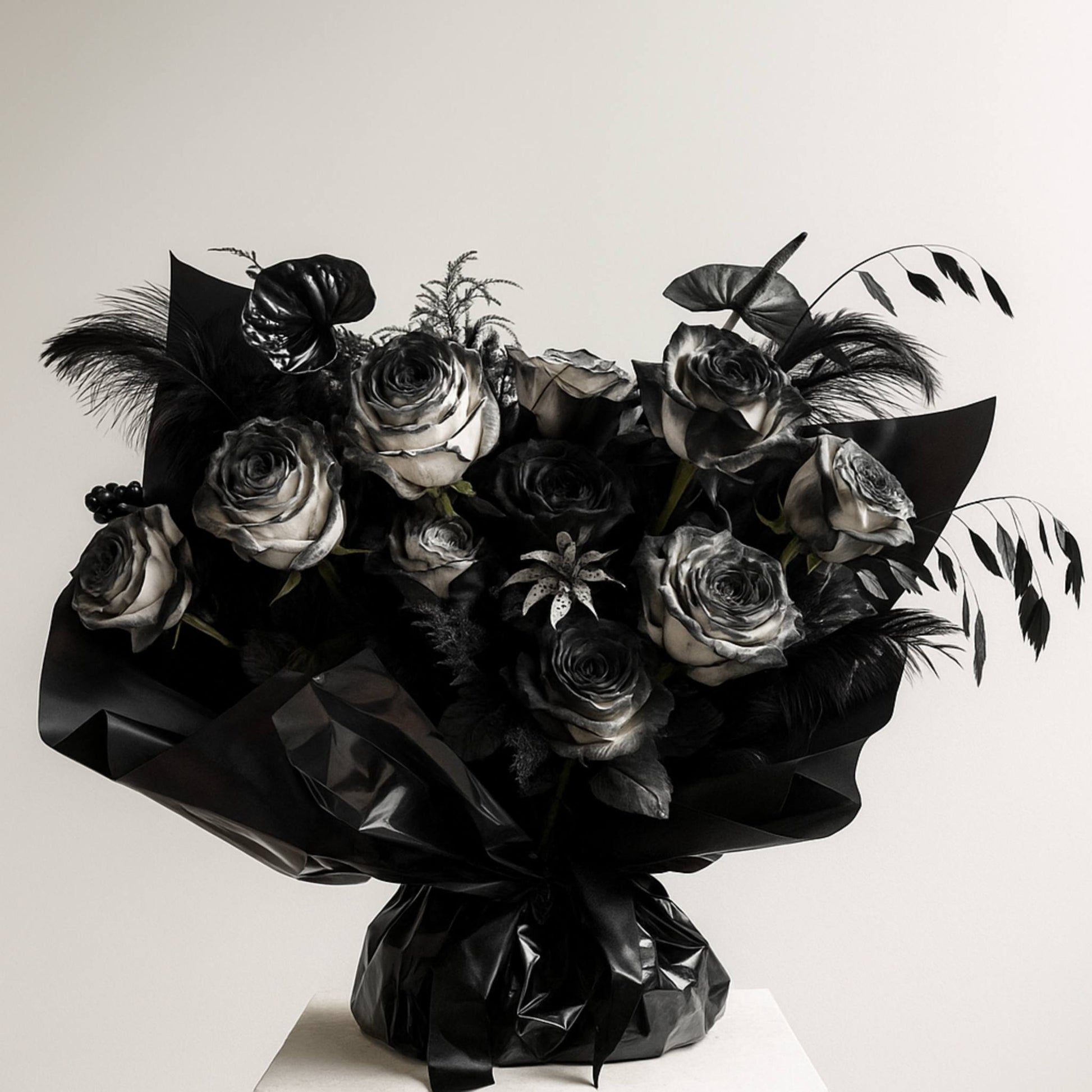 Bouquet of black and white roses with feathers on a light background