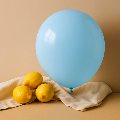 Blue 11 inch helium balloon and lemons on a beige cloth against a beige background