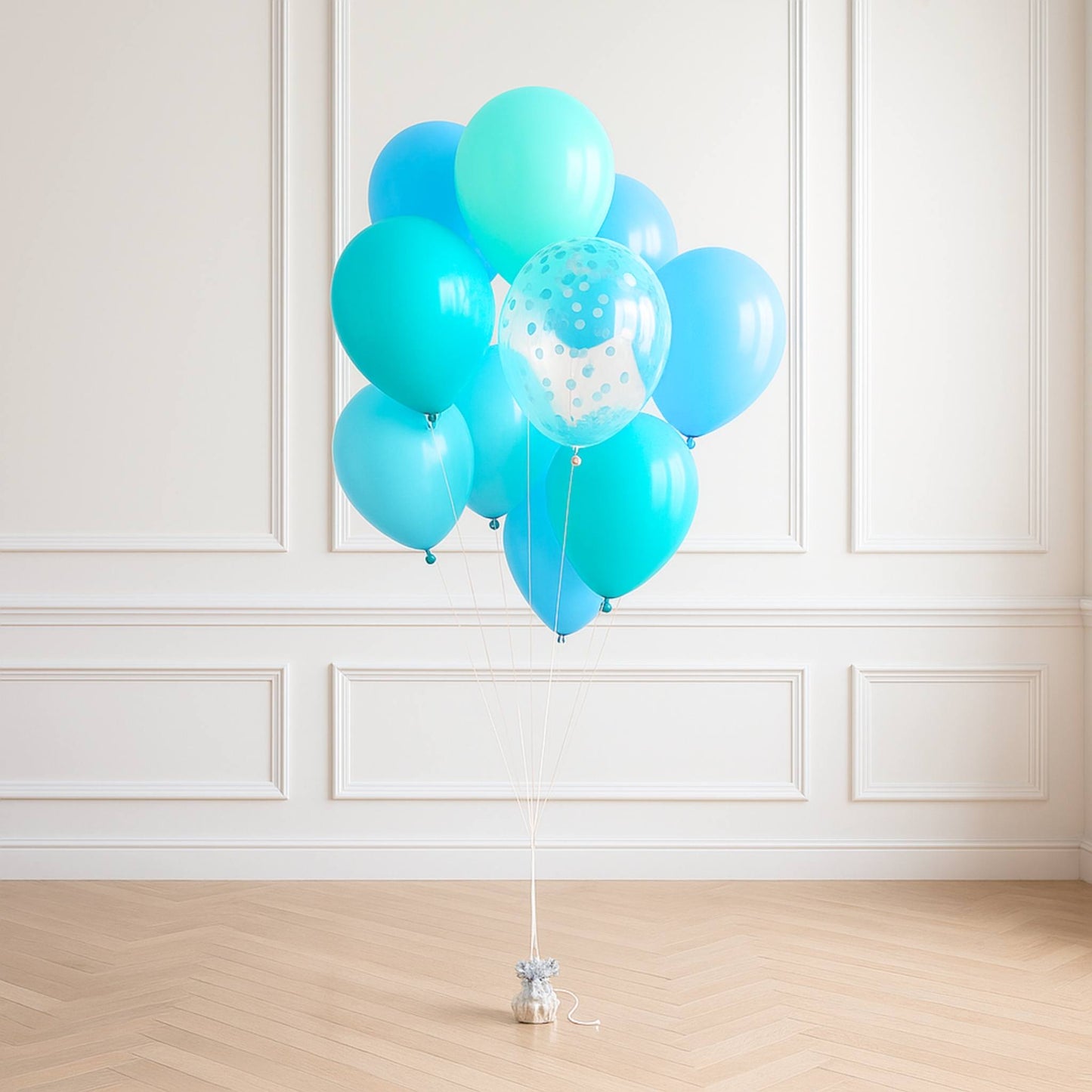 Turquoise balloons with a small white polka dot balloon against a white paneled wall.