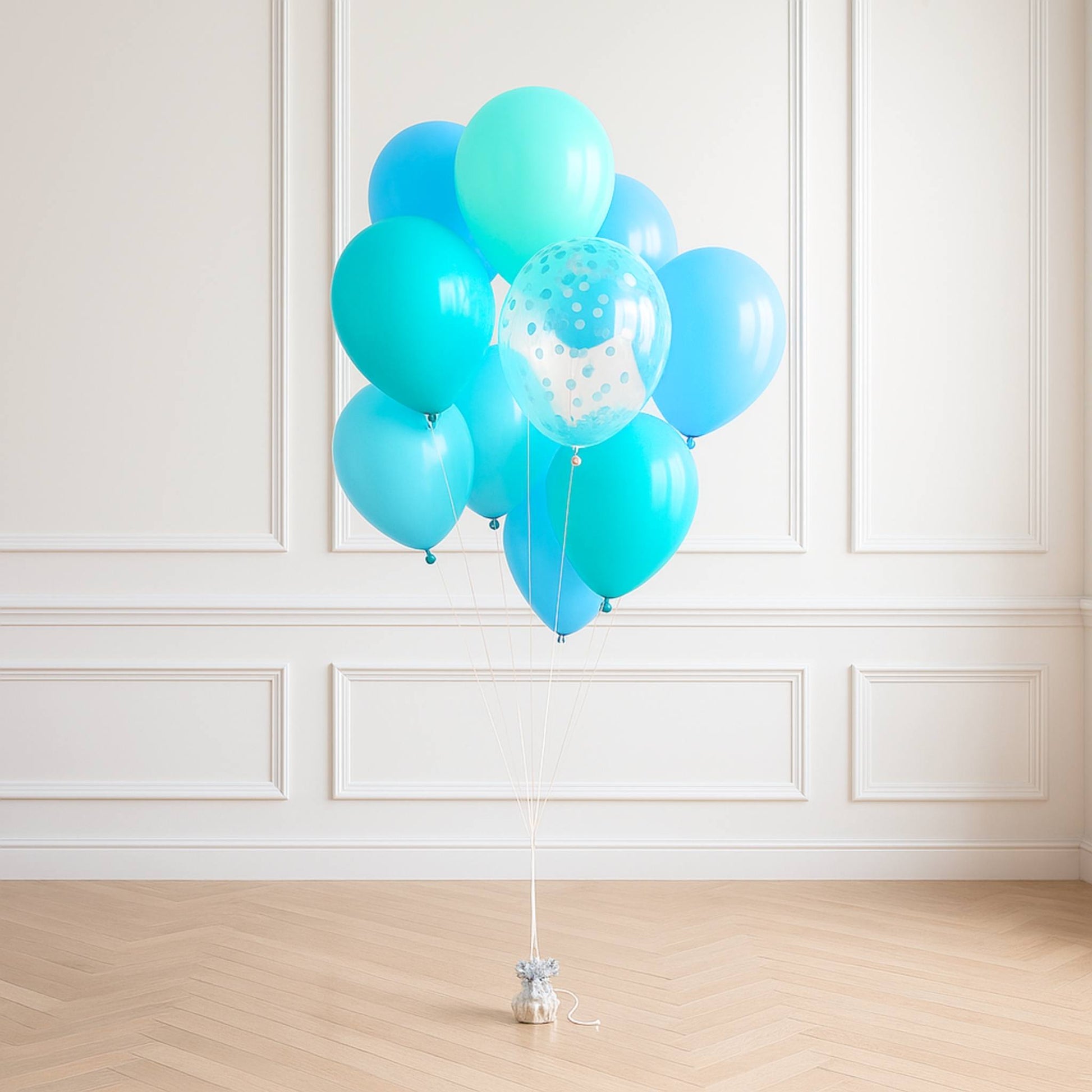 Turquoise balloons with a small white polka dot balloon against a white paneled wall.