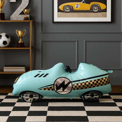 Inflatable toy car with racing design on a checkered floor against a gray wall with framed picture of a race car.