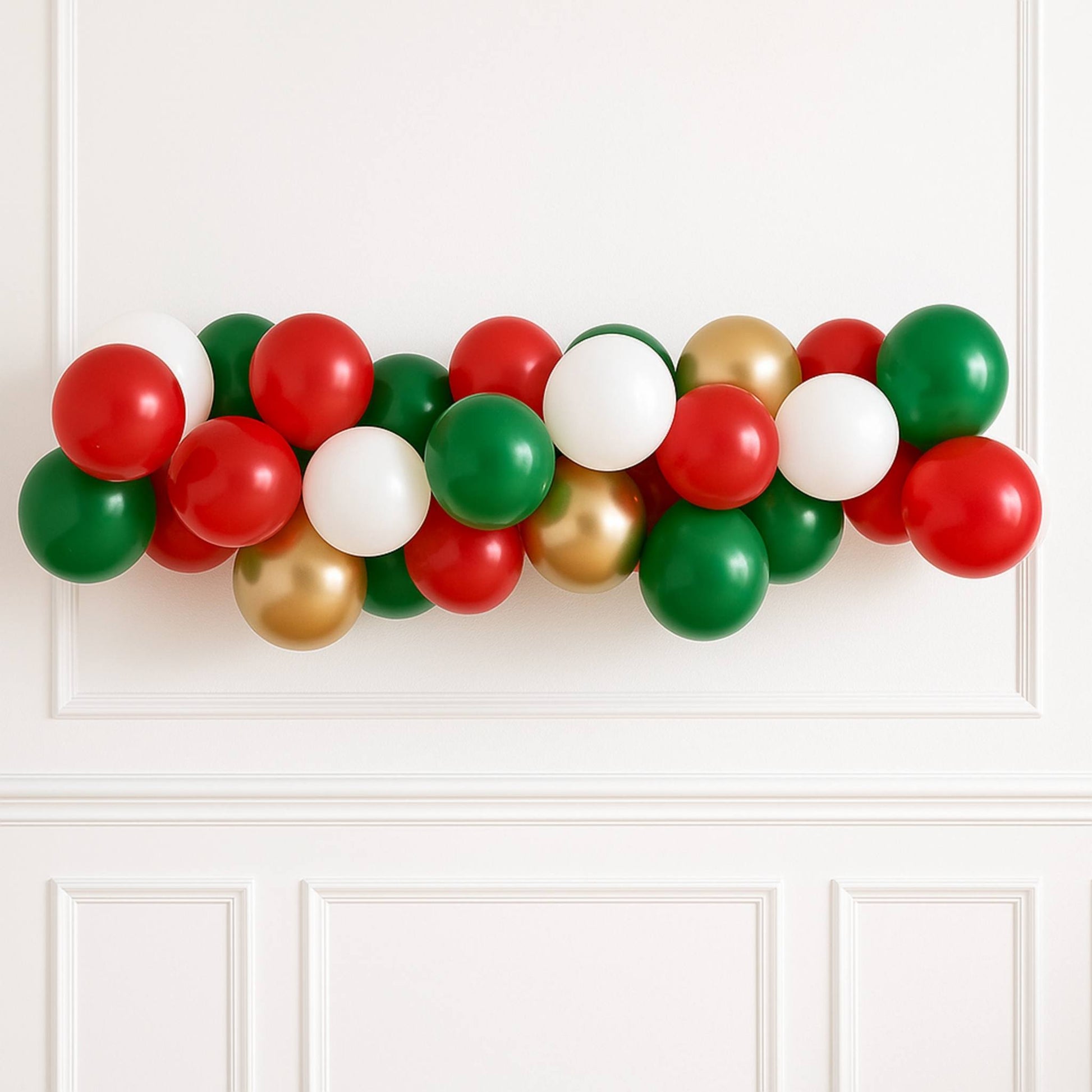 Balloon garland in red, green, and gold on a white wall