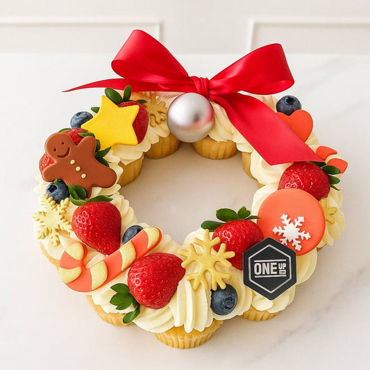Decorative Christmas cupcake wreath with a red bow, berries, and candy on a white background