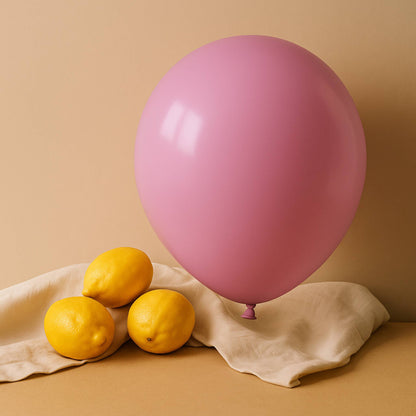 Pink 11 inch helium  balloon and lemons on a beige surface with a beige background