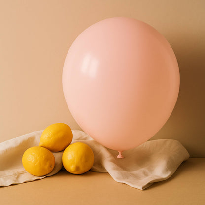Pink 11 inch helium balloon and lemons on a beige surface with a beige background