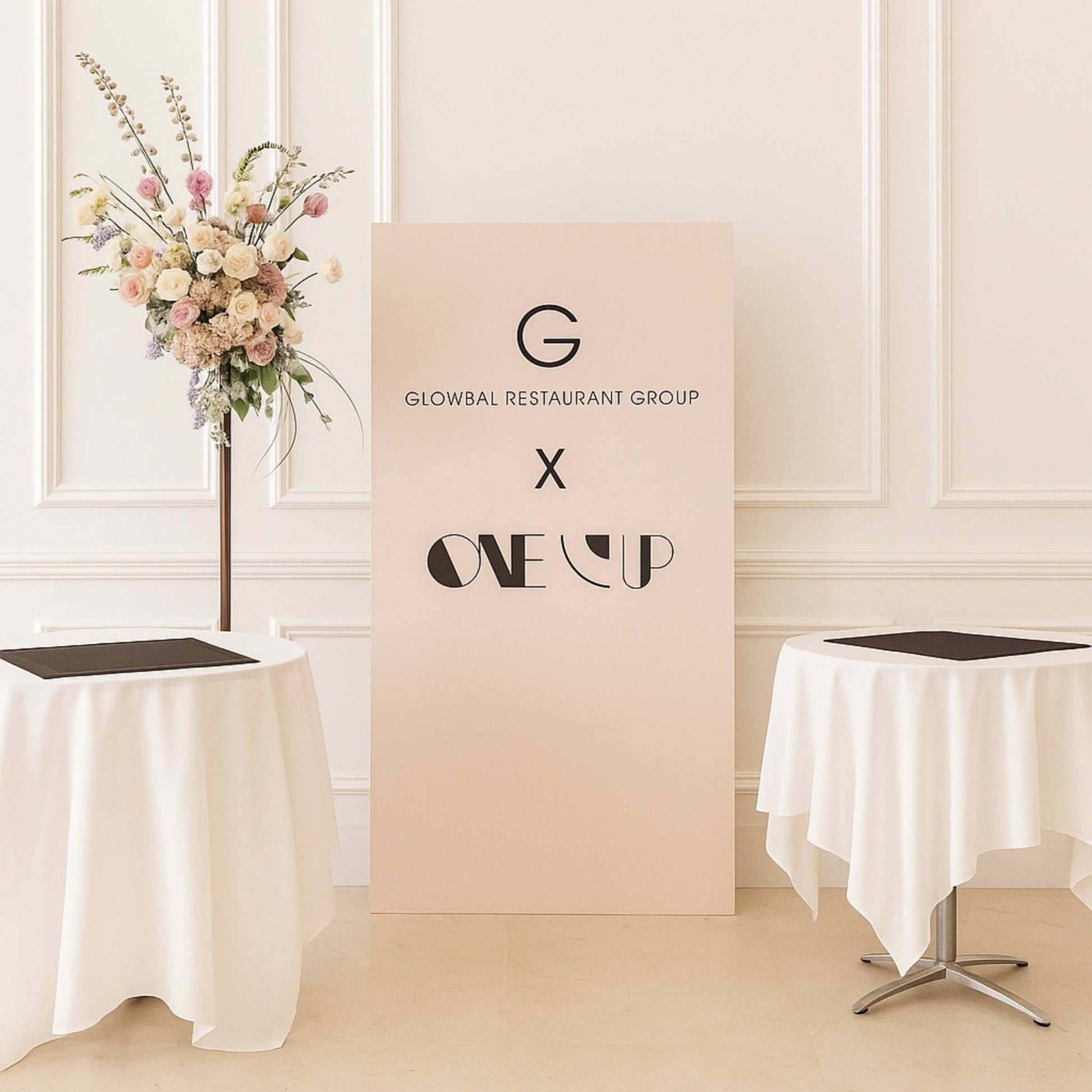 Decorative setup with floral arrangement and 'Glowbal Restaurant Group' and 'One Up' branding.