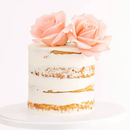 Small cake with gold accents and pink roses on a white background