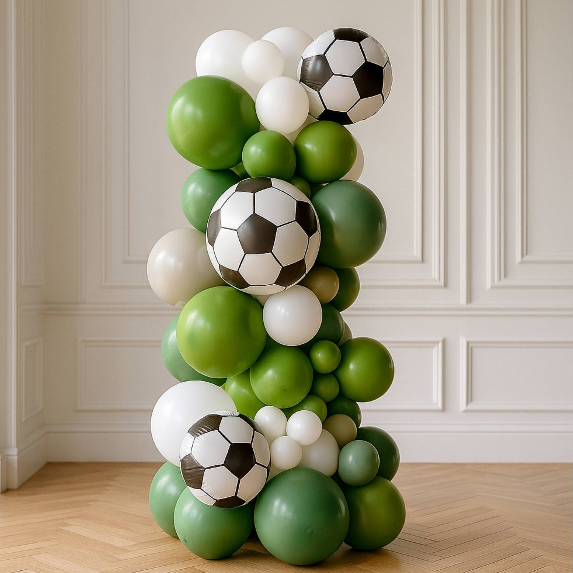 Balloon arch with soccer ball designs against a white paneled wall.