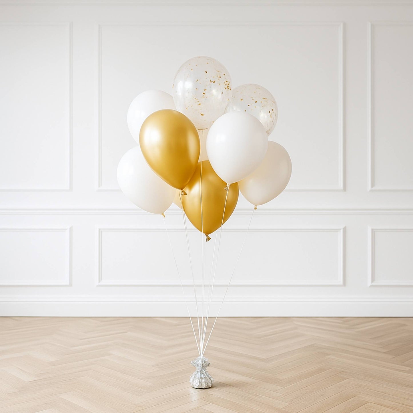 Gold and white balloons on a stand against a white wall.