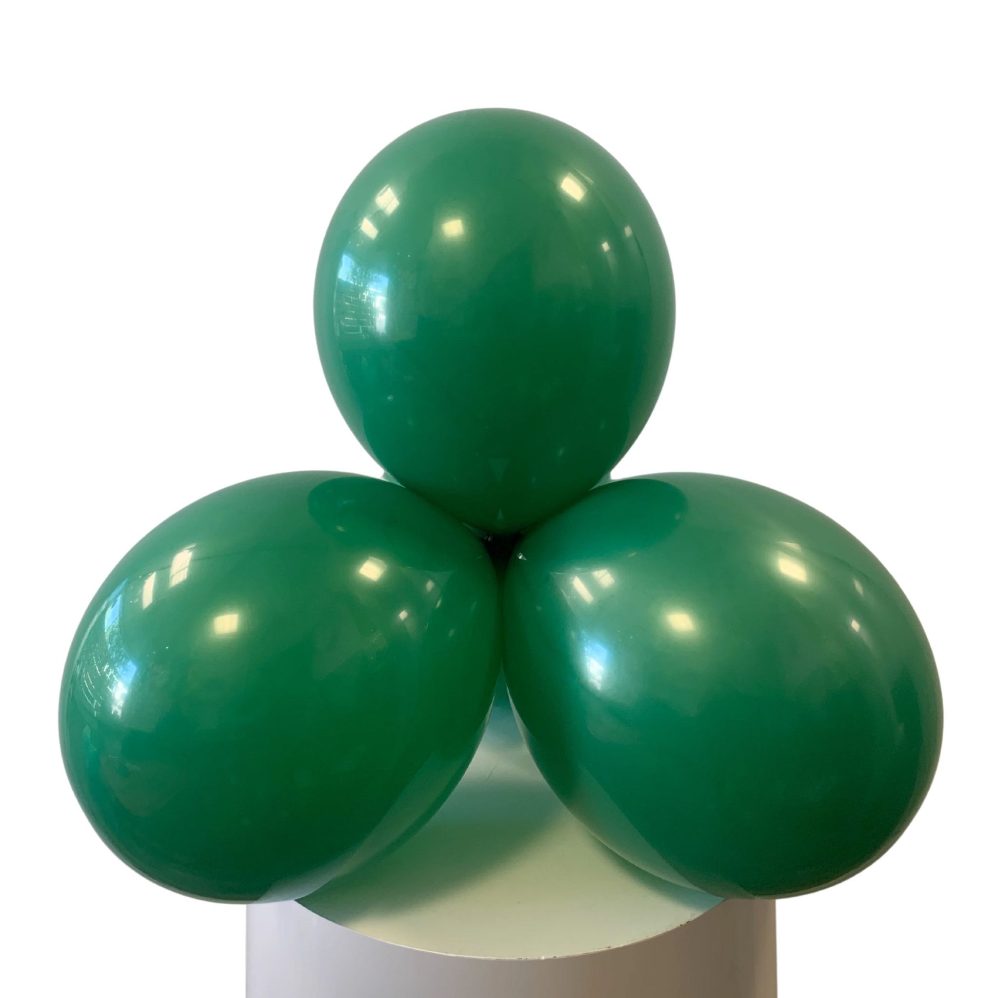 Three green balloons stacked on a white cylindrical base with a white background
