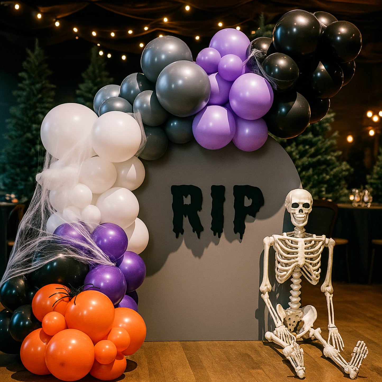 Halloween-themed balloon arch with 'RIP' sign and skeleton figure.