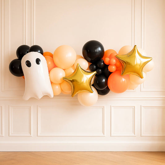 Halloween-themed balloon arrangement with a ghost decoration on a white paneled wall.
